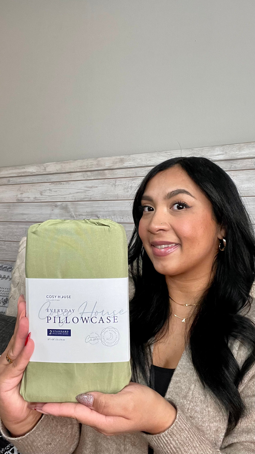 A smiling customer displaying a packaged pair of Everyday pillowcases.