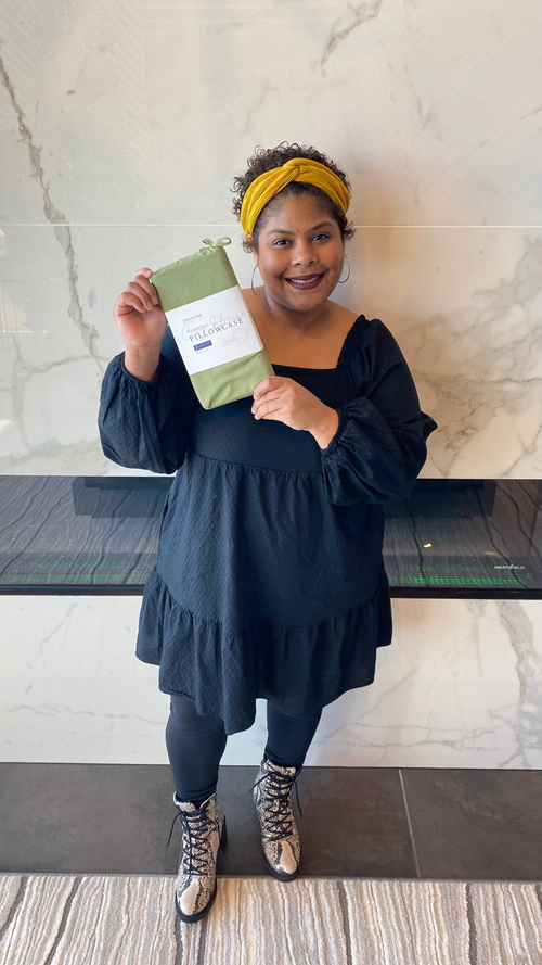 A standing customer showing a packaged pair of Everyday pillowcases.