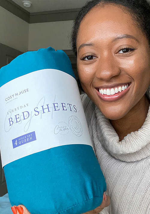 Another happy female customer is holding a packaged set of Cosy House Collection’s Everyday Bed sheets.