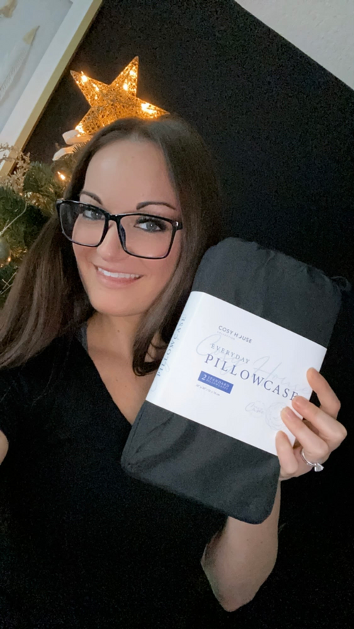 A satisfied customer flexing a packaged pair of Everyday pillowcases.