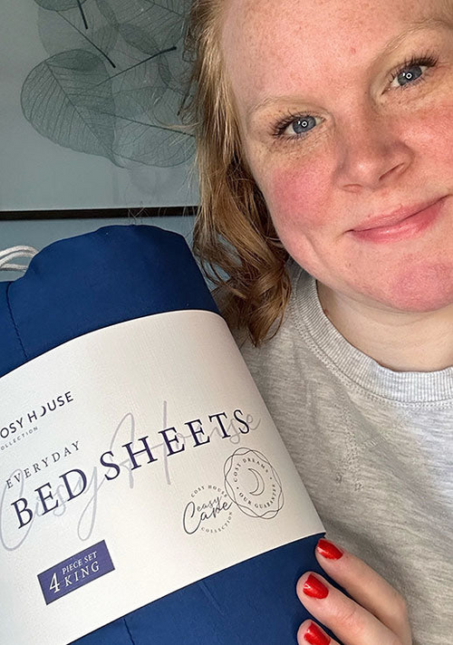 Another happy female customer is holding a packaged set of Cosy House Collection’s Everyday Bed sheets.