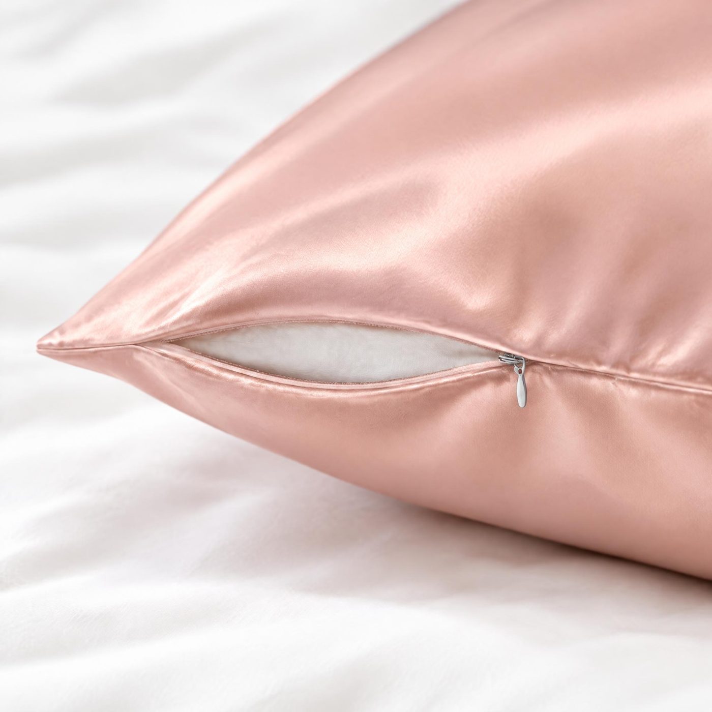 Close-up of the half-open hidden zipper on a blush-pink silk pillowcase