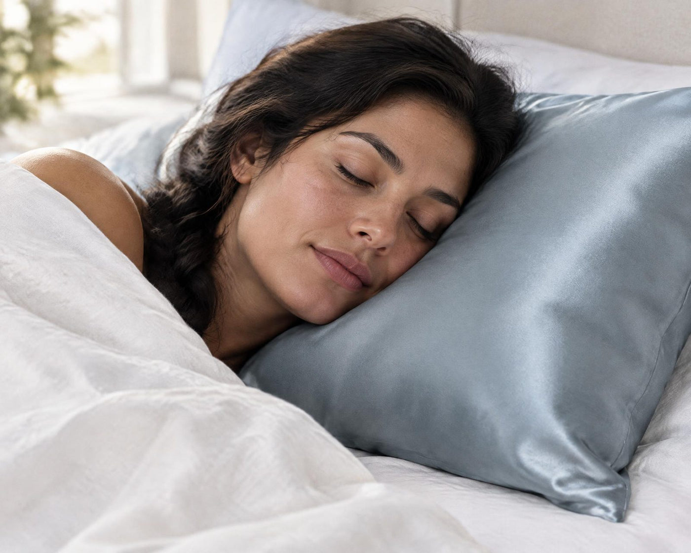 Woman asleep on her side, her cheek on an ash-blue silk pillowcase